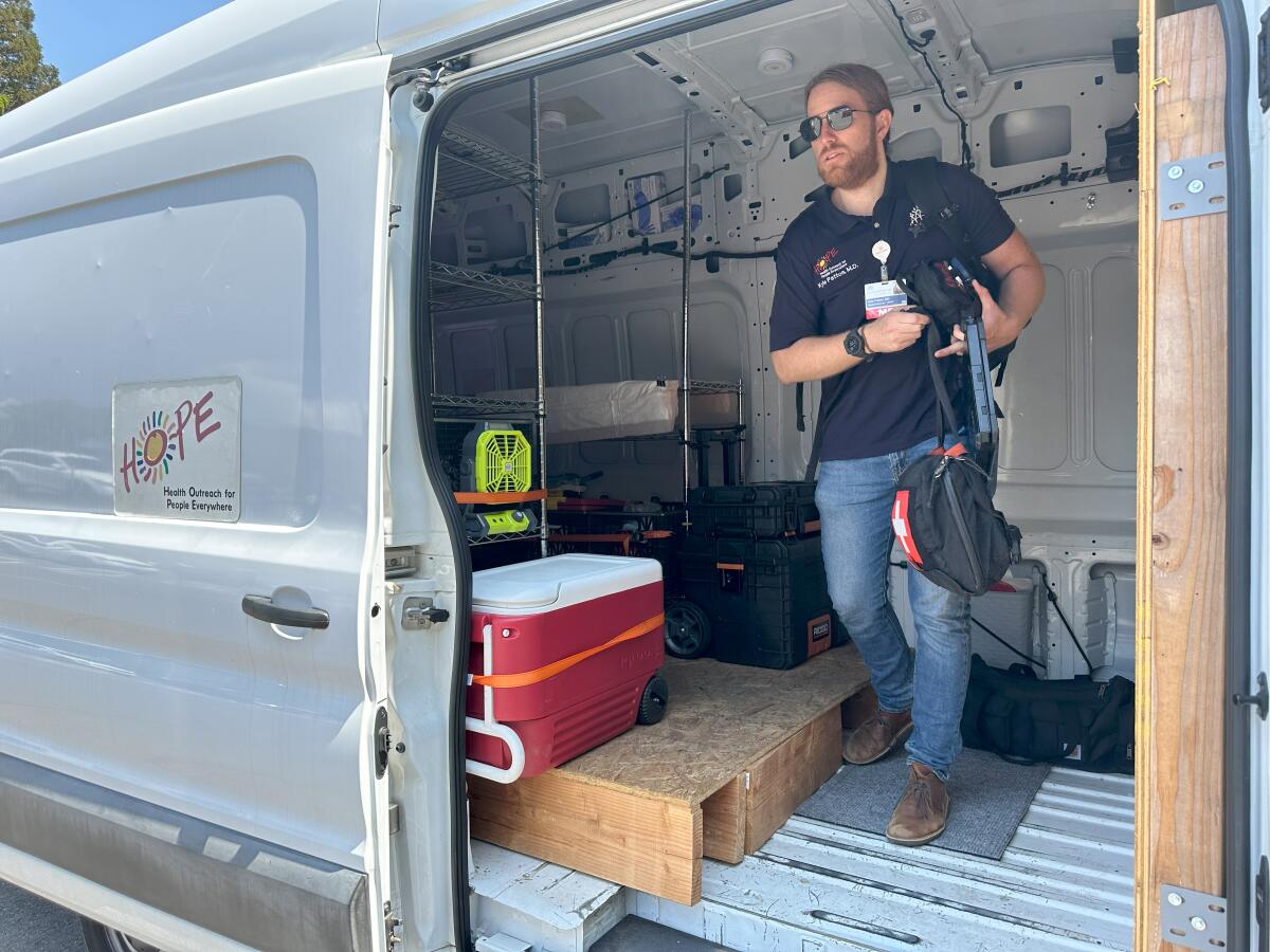 A standing person is about to exit a tall van.