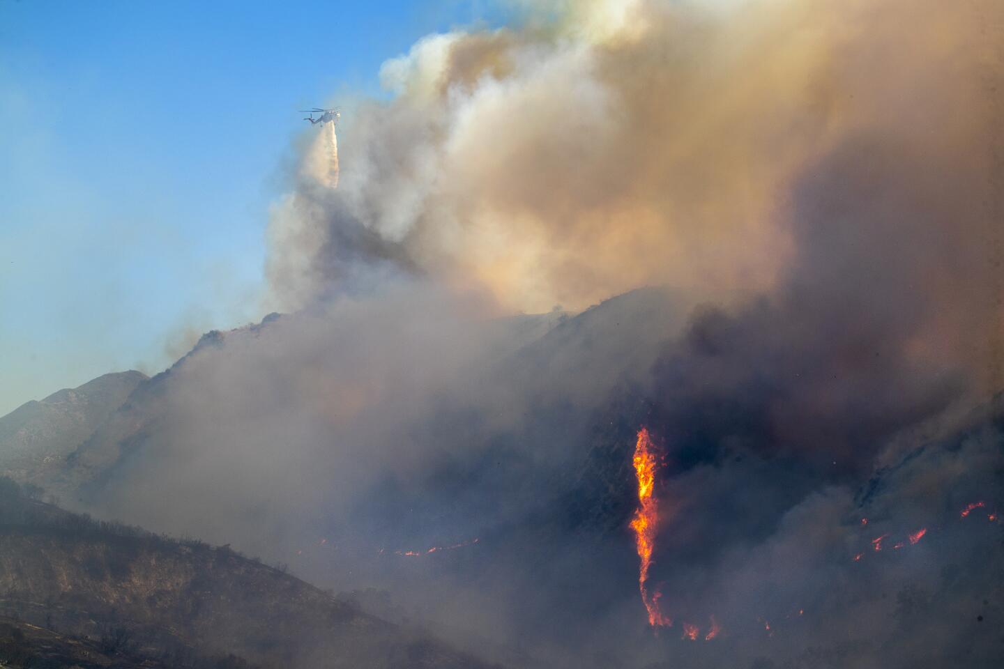 A firefighting helicopter makes a drop on the Silverado fire, which has been fanned by gusty Santa Ana winds for a second day