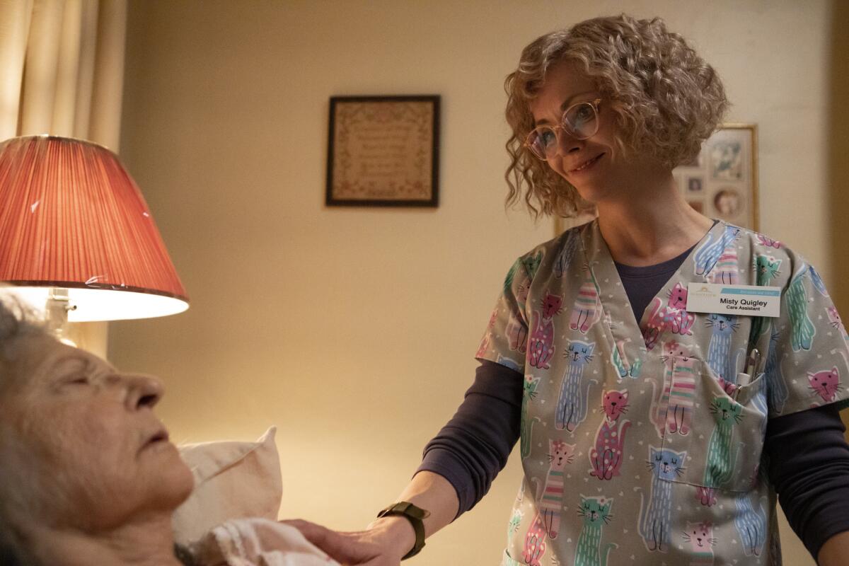 A nurse smiles down on a patient at a nursing home.