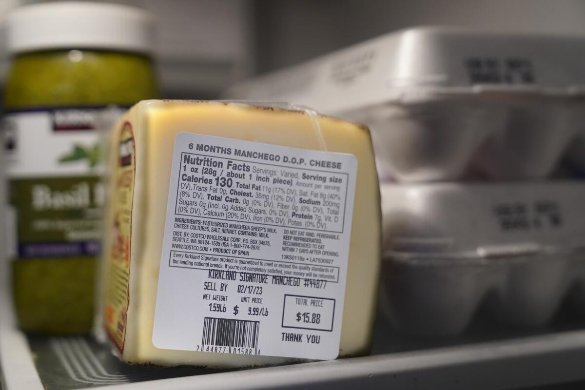 Cheese and eggs stamped with "sell by" dates on a refrigerator shelf.