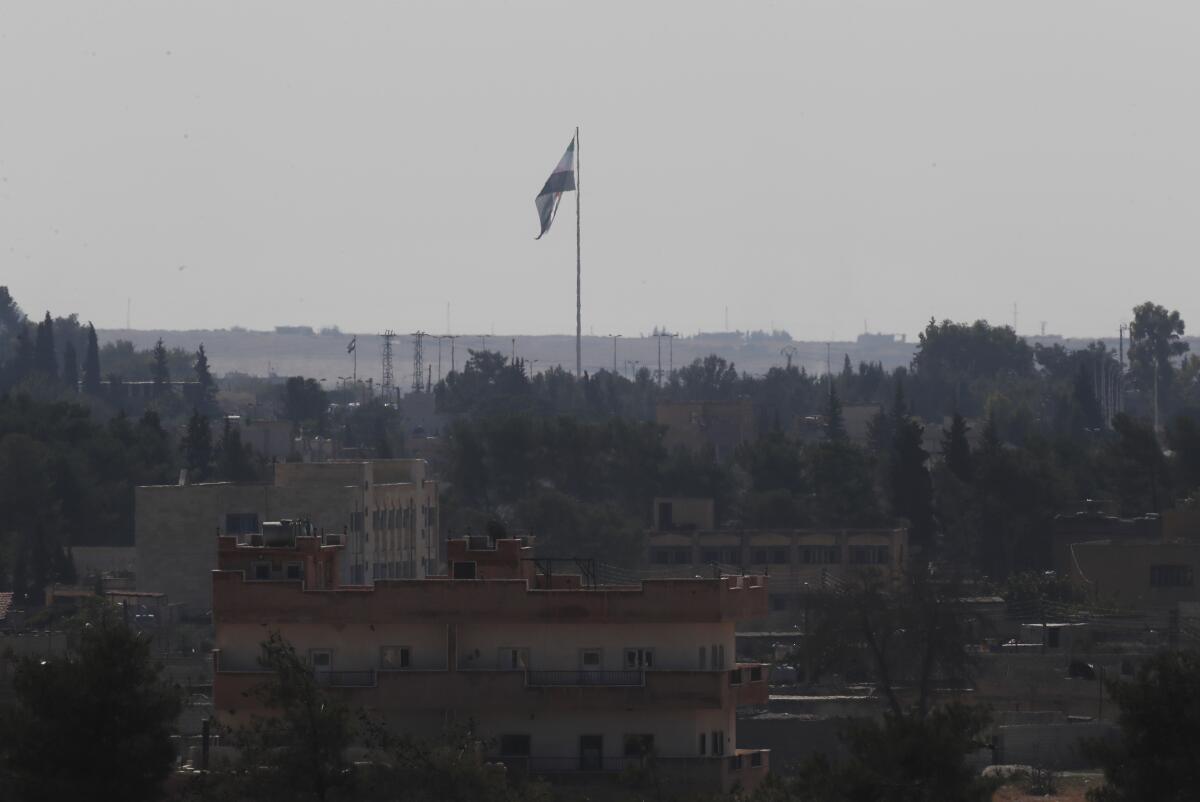 In this photo taken Oct. 23, 2019, from Akcakale, Turkey, the Syrian opposition flag can be seen across the border in Tal Abyad, Syria.