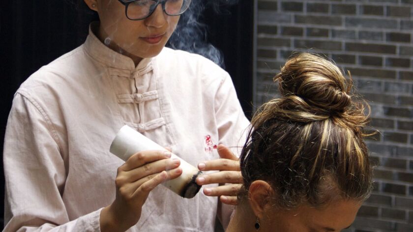 Un voyageur reçoit un traitement de moxibustion, une thérapie médicinale qui brûle de l'armoise séchée près de points particuliers du corps.