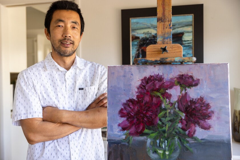 Pil Ho Lee stands next to his most recent oil painting titled "Peonies," at his home in Orange on Wednesday.