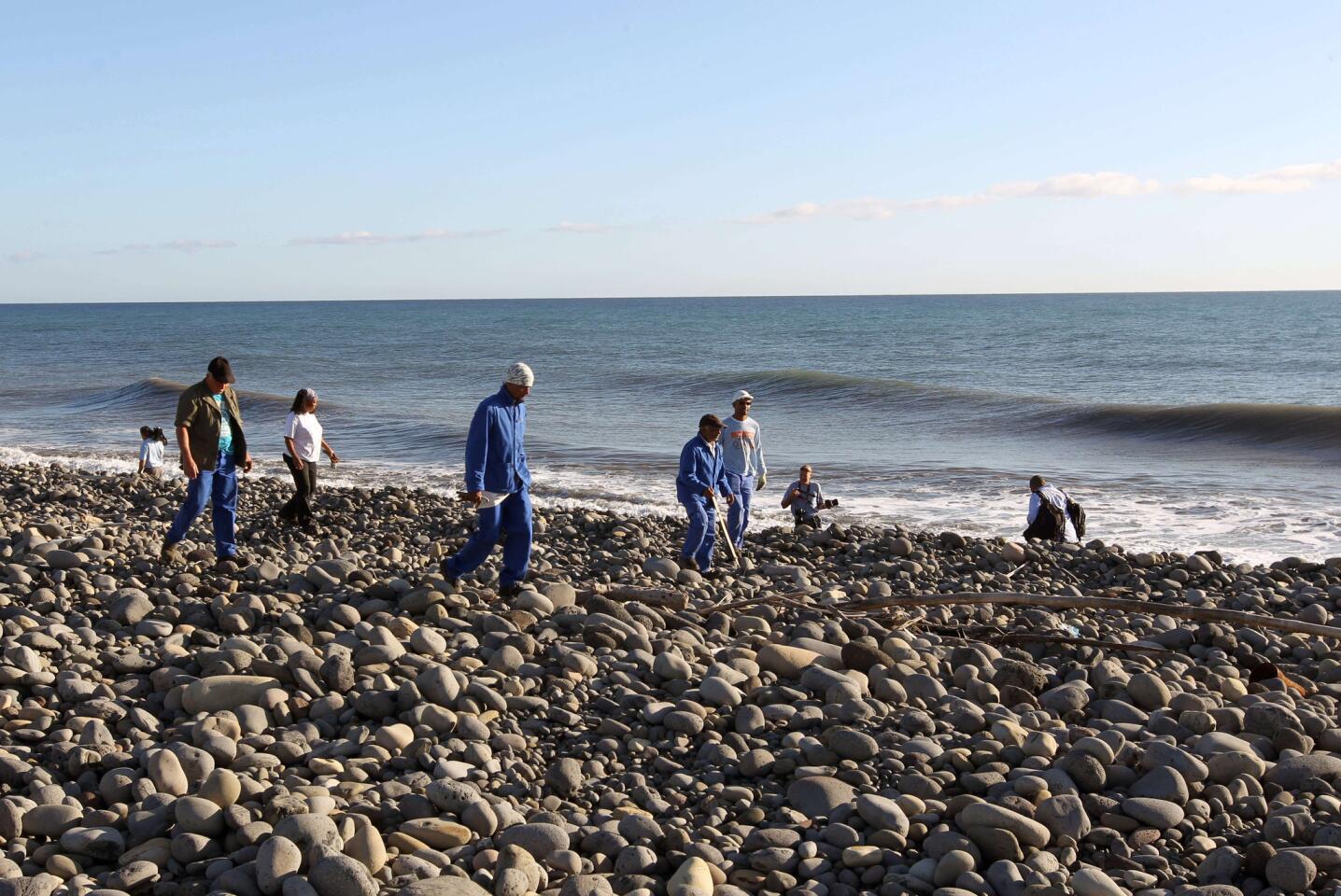 Volunteers of the "3 E" (Eastern Environnement and Economy) association — usually in charge of costal cleaning — search for more potential plane debris and items on the shore in Saint-Andre, Reunion Island, on July 31, 2015.