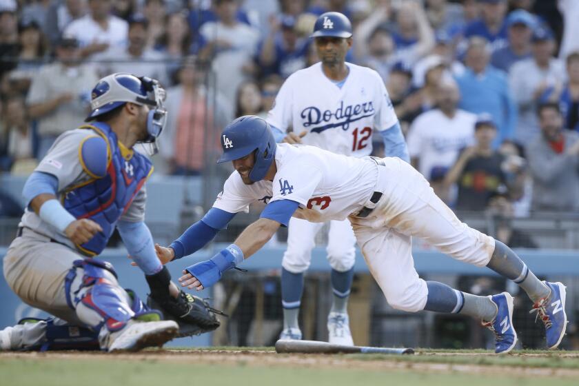 Los Angeles Dodgers' Chris Taylor, center, slides away from the tag by Chicago Cubs catcher Willson Contreras, left, to score with third base coach Dino Ebel, above right, watching on a single by Russell Martin during the eighth inning of a baseball game in Los Angeles, Sunday, June 16, 2019. (AP Photo/Alex Gallardo)