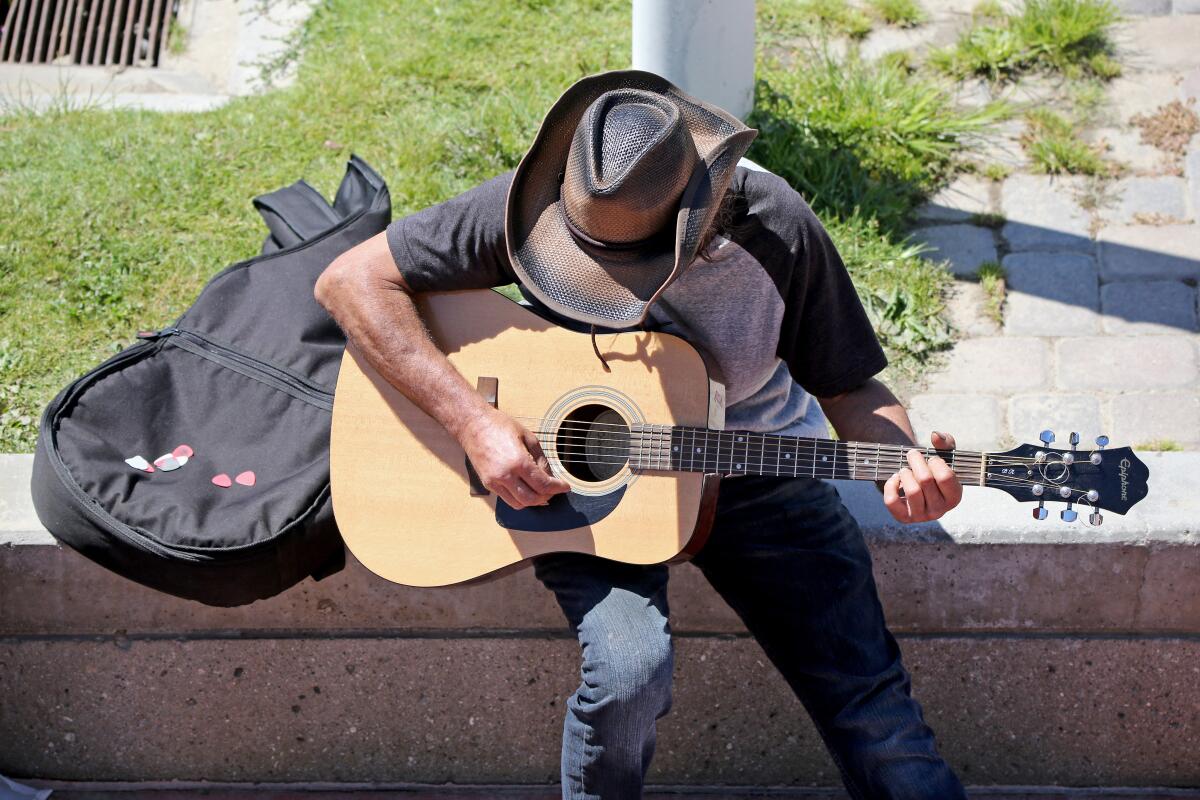 A man plays the guitar near the Huntington Beach pier on July 31, 2020.