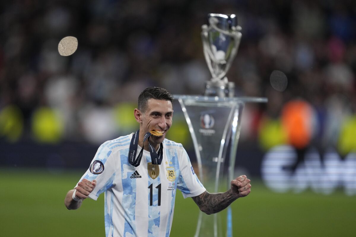 Ángel Di María raises his arms after receiving a medal on the field.