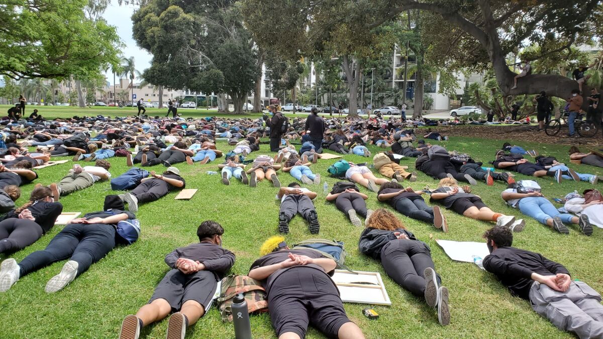 Youth protesters simulated the pose of a person being arrested Monday afternoon near Balboa Park after marching to the area from San Diego City College in downtown San Diego.