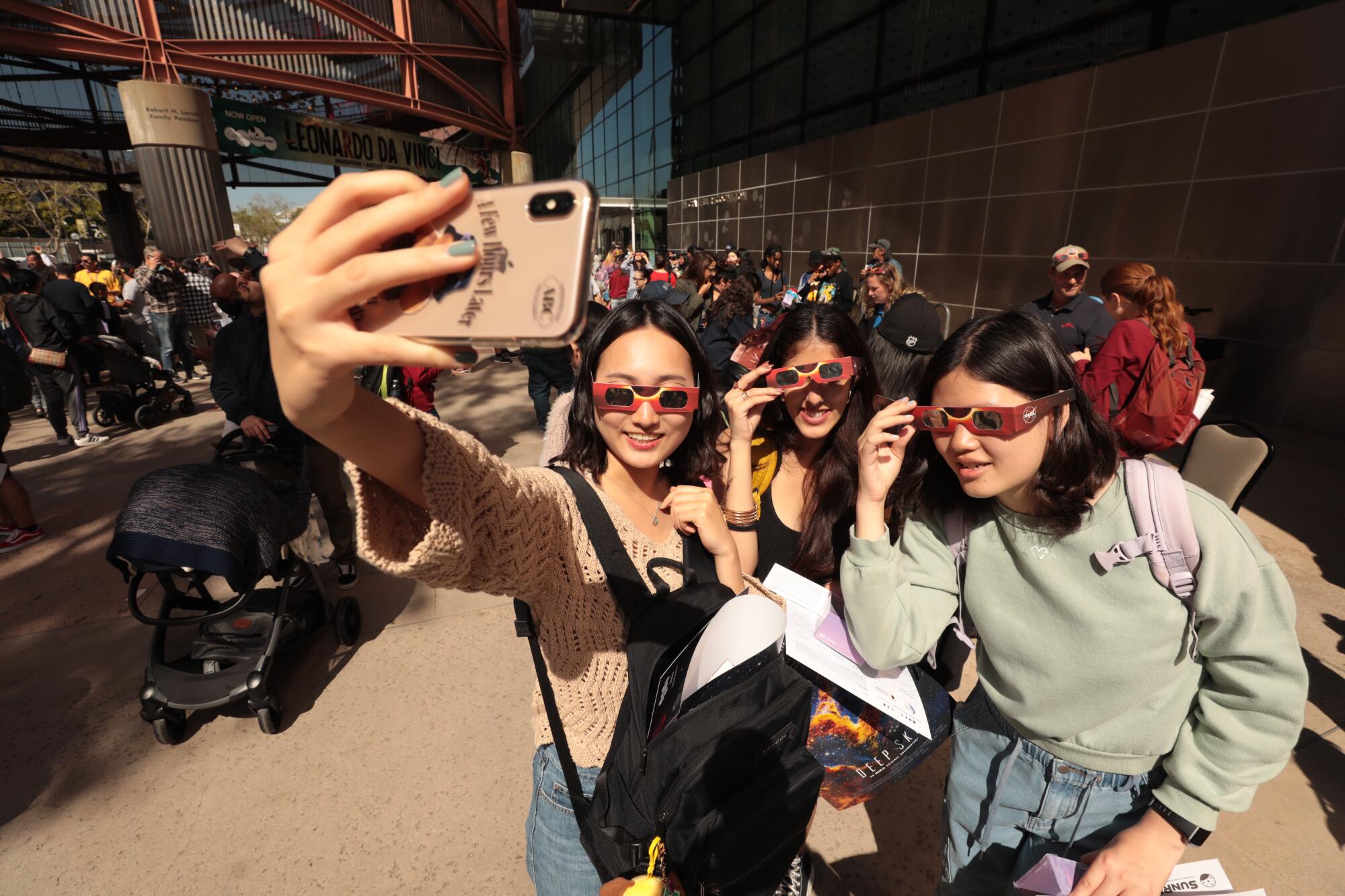USC students take a selfie as part of the crowd that gathered at the California Science Center wearing protective eye-wear.