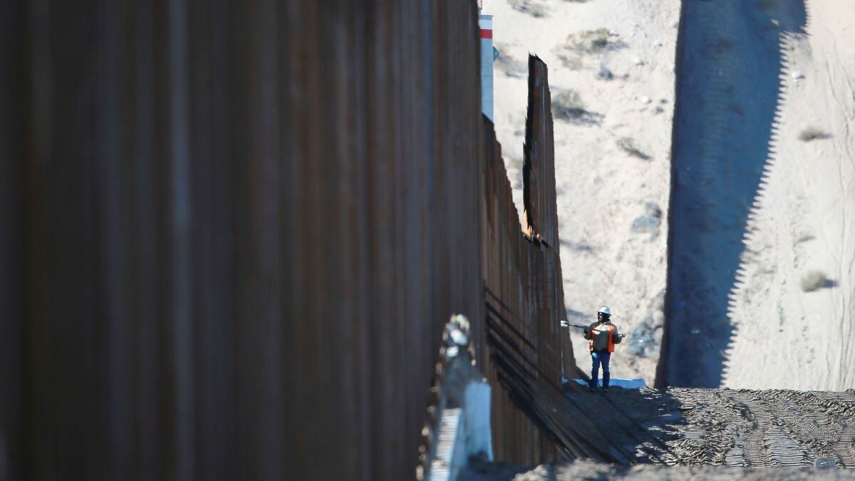A worker is dwarfed by the border fence which is under construction Wednesday, Jan. 25, 2017, in Sunland Park, N.M. across from Anapra, in Ciudad Juarez, Mexico.