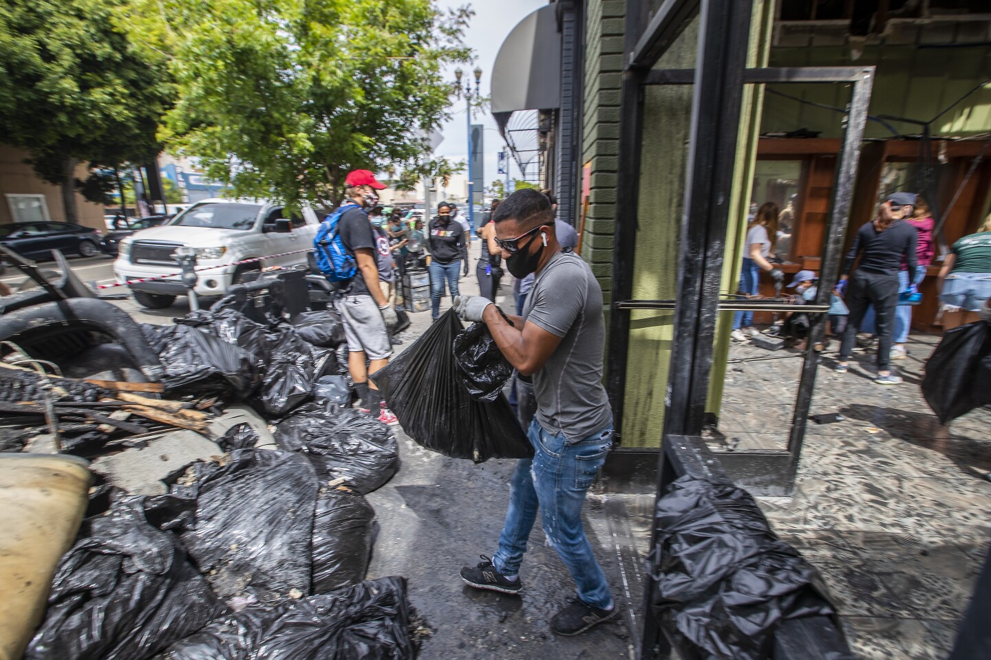 LONG BEACH, CA - JUNE 01: After looters set fire and destroyed the building Sunday evening, a large group of volunteers help clean up Legacy Beauty & Barber Salon, near the intersection of Pine Ave. and 7th Street Monday, June 1, 2020 in Long Beach, CA. (Allen J. Schaben / Los Angeles Times)