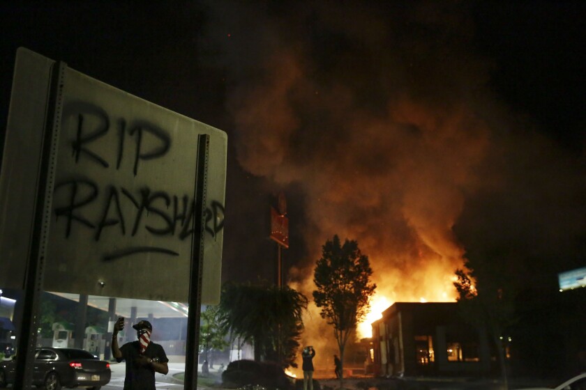 File-In this Saturday, June 13, 2020 file photo, "RIP Rayshard" is spray-painted on a sign as flames engulf a Wendy's restaurant where Rayshard Brooks was shot and killed by police in Atlanta. Three people have been indicted on arson charges in the burning of the Wendy’s restaurant in Atlanta where a police officer fatally shot Rayshard Brooks in June 2020. A Fulton County grand jury on Thursday, Jan. 27, 2022 indicted 24-year-old Chisom Kingston, 35-year-old John Wade and 31-year-old Natalie White on two counts each of first degree arson and one count of conspiracy to commit first degree arson.(AP Photo/Brynn Anderson, File)