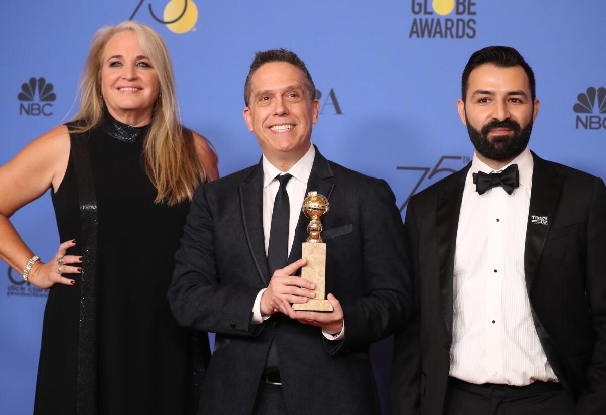 La productora Darla K. Anderson, el director Lee Unkrich y el guionista Adrian Molina posan tras recibir el premio por "Coco".