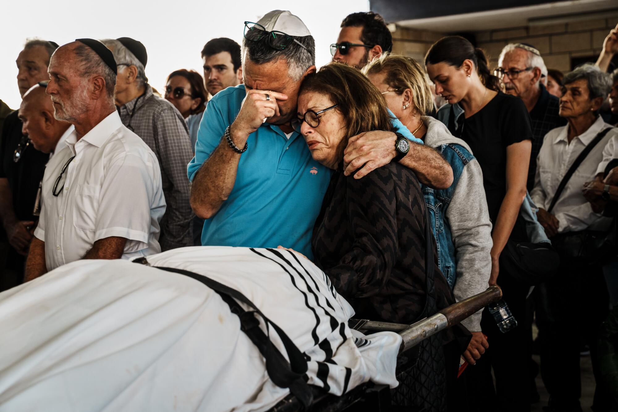 Two people embrace as they pay their last respect to MirelaOs son Daniel Levy who was killed in the BeOeri Kibbutz