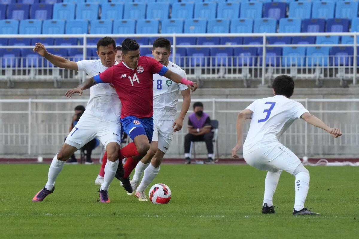El futbolista costarricense Orlando Galo (centro) pelea por un balón con el uzbeko Otabek Shukurov 