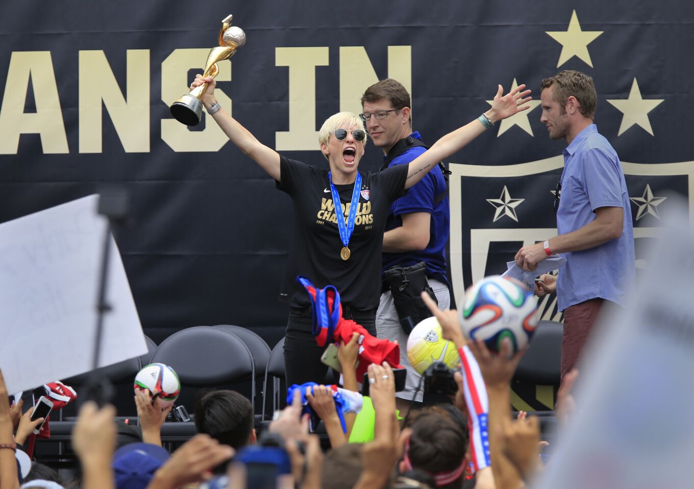 Midfielder Megan Rapinoe hoists the trophy the team was awarded for winning the Women's World Cup.