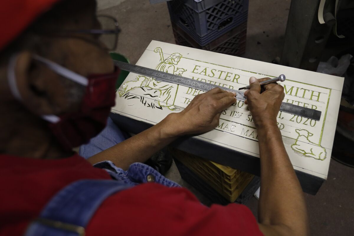 Hosea Knox, owner of Elmo's Tombstone Service cuts out the lettering Thursday, May 28, 2020, on a stencil glued to a granite stone in his shop on Chicago's Southside. Knox and assistant Leon Brown take pride in distinguishing themselves from the modern "computerized laser" cut, a technique that Knox claims is just a "skin" cut that will fade over time. "It is just like a photograph, it is not cut in there deep," Knox said, "When I cut a stone, it is down in there and will withstand the weather." (AP Photo/Charles Rex Arbogast)