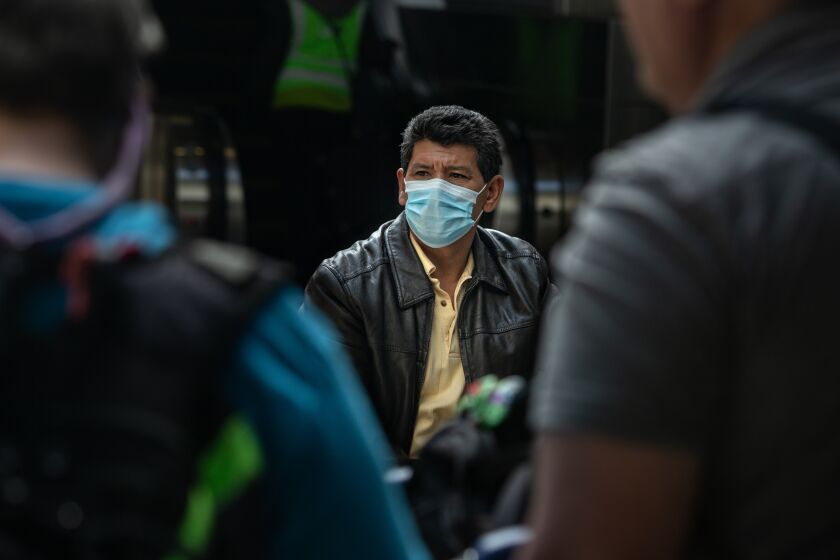 Los Angeles, CA., March 15, 2020 - A traveler sits outside Tom Bradley International Terminal at LAX after returning from abroad on Sunday, March 15, 2020 in Los Angeles, California. As Trump's new travel restrictions kick in a flood of people returning from Europe and various other countries endure long lines because of health screening. (Jason Armond / Los Angeles Times)