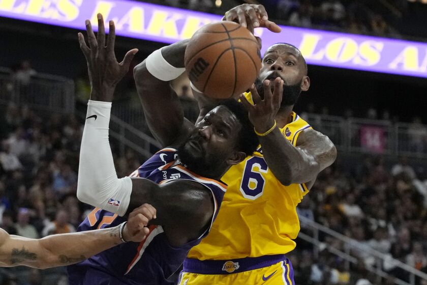 Phoenix Suns center Deandre Ayton (22) and Los Angeles Lakers forward LeBron James (6) battle for the ball during the first half of a preseason NBA basketball game Wednesday, Oct. 5, 2022, in Las Vegas. (AP Photo/John Locher)