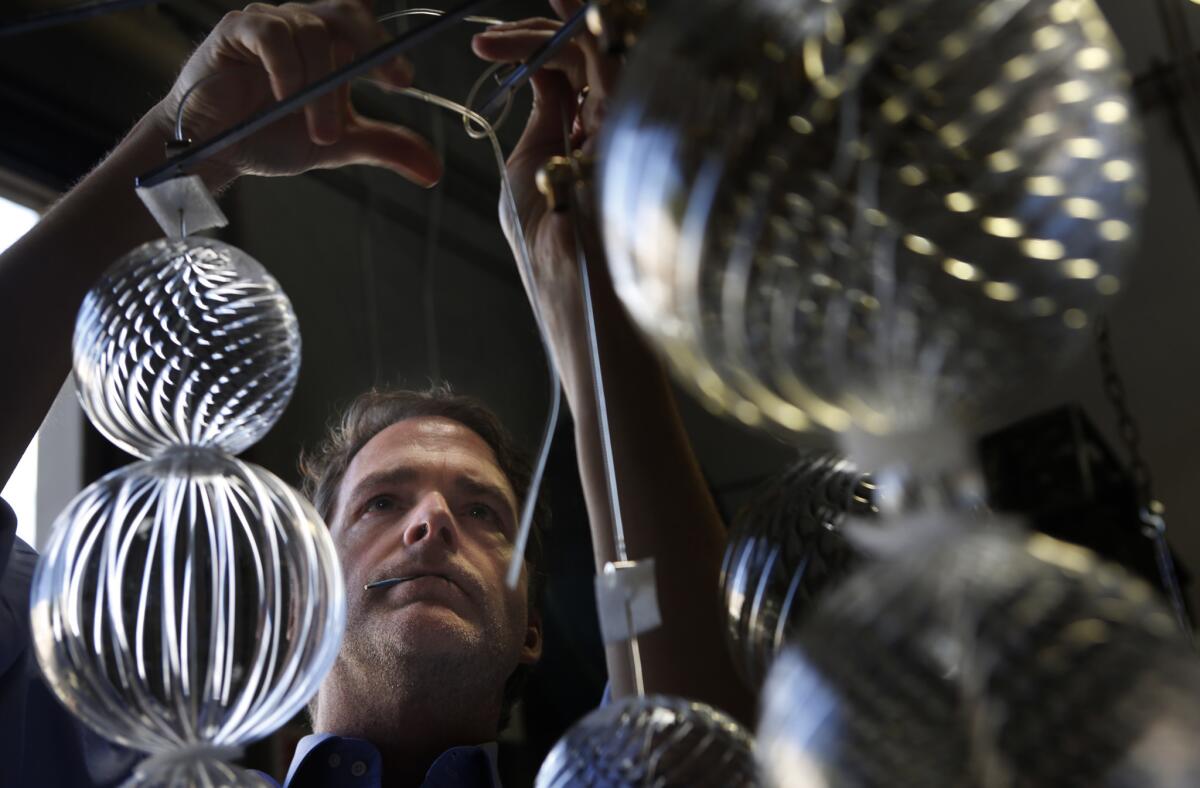 In his Irvine studio, Thomas Fuchs assembles a custom designed chandelier made of individual glass spheres hand blown in Murano, Italy. The home accessories designer from New York City is opening a new glass blowing factory in Los Angeles, where he will be making new glassware collections in an exclusive collaboration with Saks.