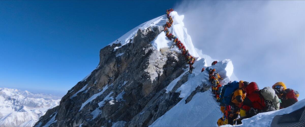 A line of climbers on a snowy mountain ridge.
