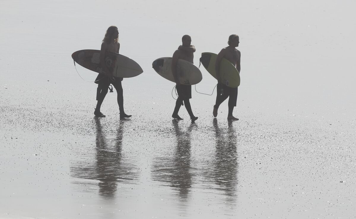 Surfers walk at Blacks Beach on Friday, December 13, 2019 in San Diego, California.