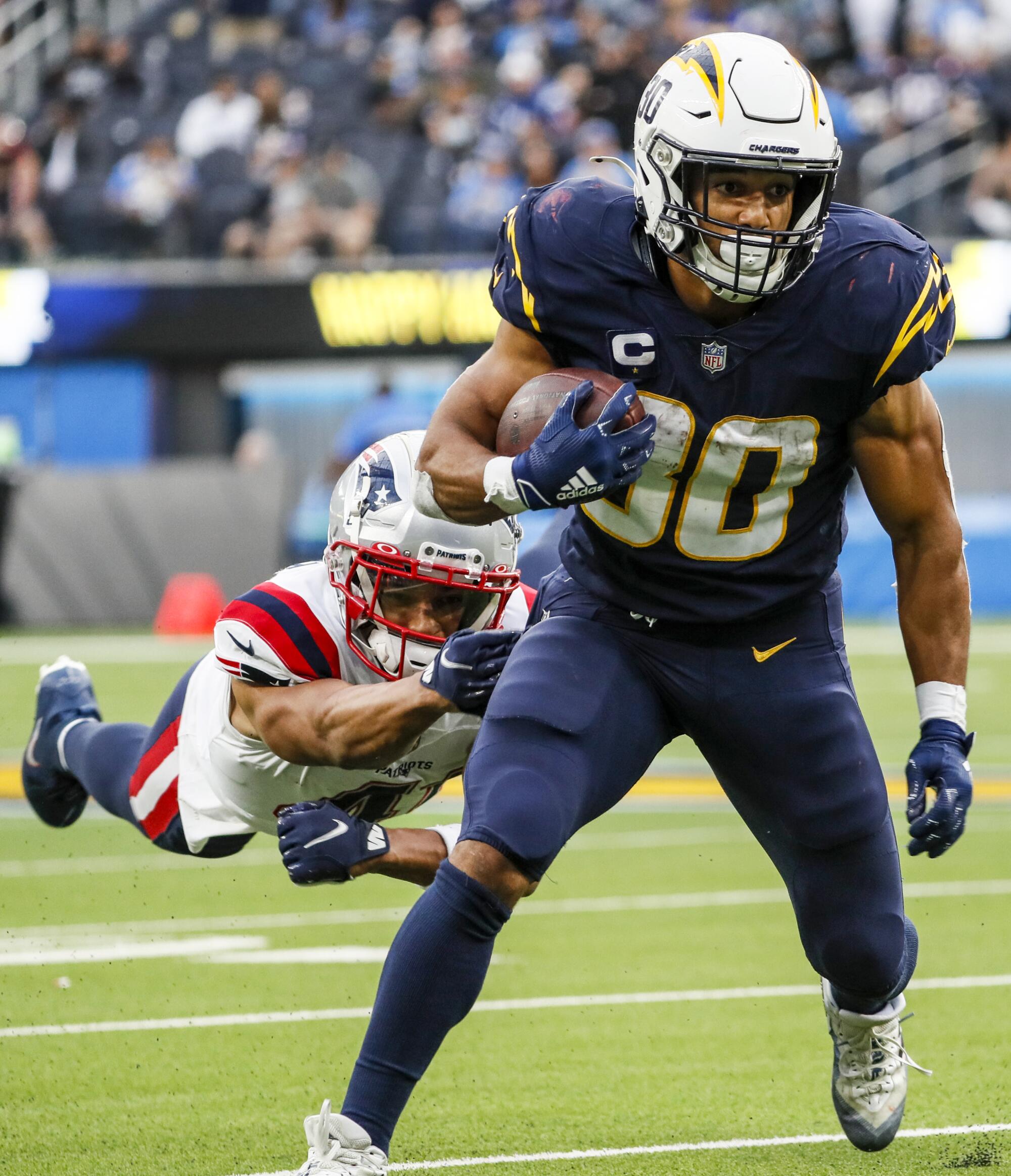 Chargers running back Austin Ekeler shakes a diving tackle attempt by New England Patriots cornerback Myles Bryant.