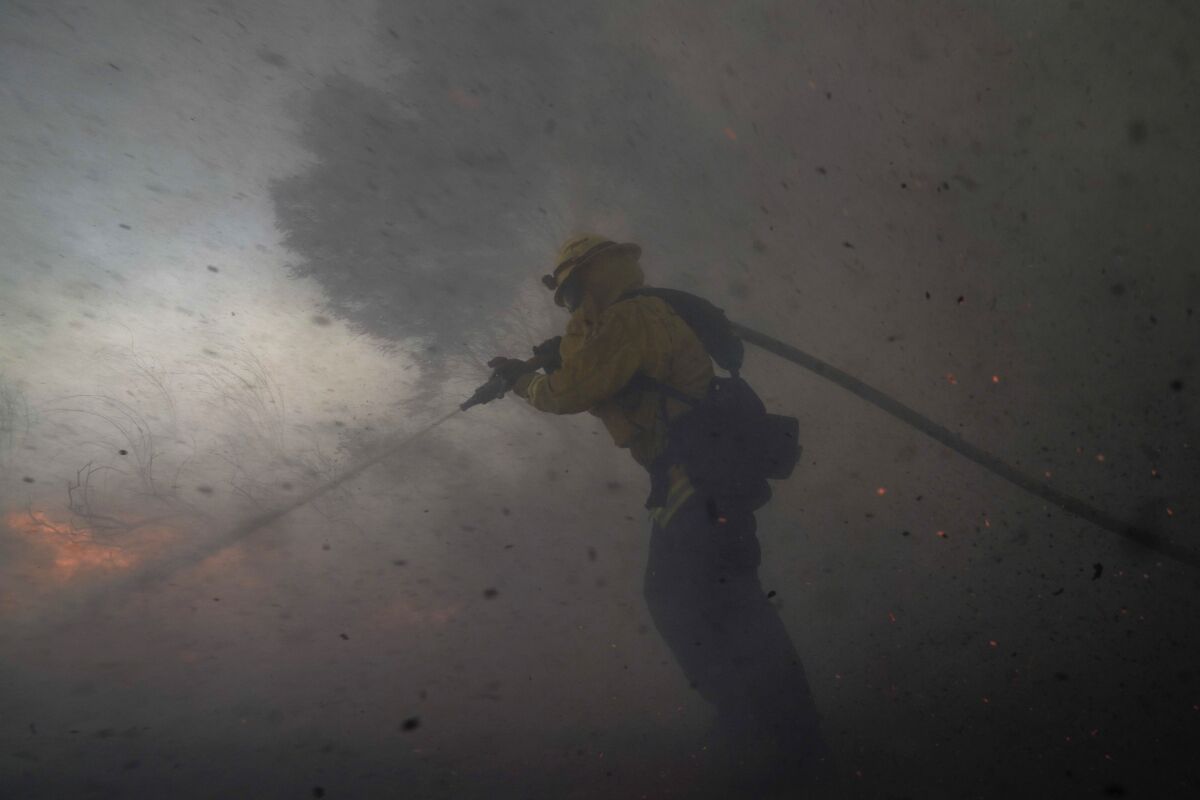 FILE - In this Monday, Oct. 26, 2020 file photo, A firefighter battles the Silverado Fire in Irvine, Calif. Two firefighters who were critically burned while trying to set backfires to slow the spread of a Southern California wildfire in October likely shouldn’t have been there in the first place given the extraordinarily dangerous conditions, according to a newly released investigation of the incident.(AP Photo/Jae C. Hong, File)