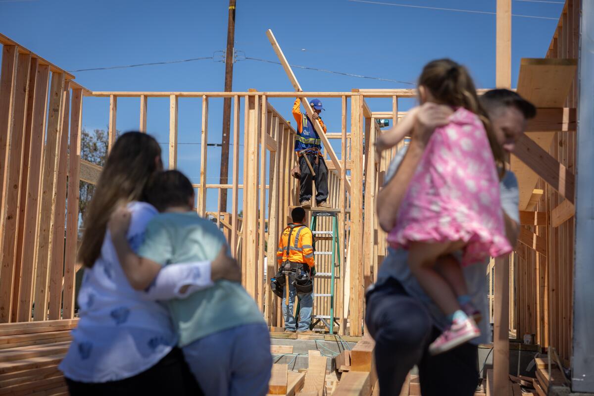 The Le Guier family look on as construction crews re-build their Pacific Palisades home.