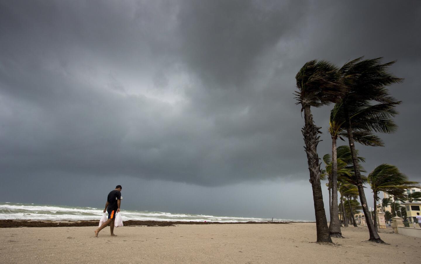 A man walks along the beach with heavy winds and threatening skies in Hollywood, Fla., as Hurricane Irma approaches the state on Sept. 9, 2017.