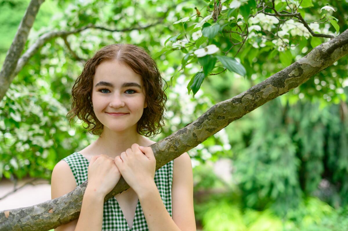 Millicent Simmonds grabs hold of a tree branch. 