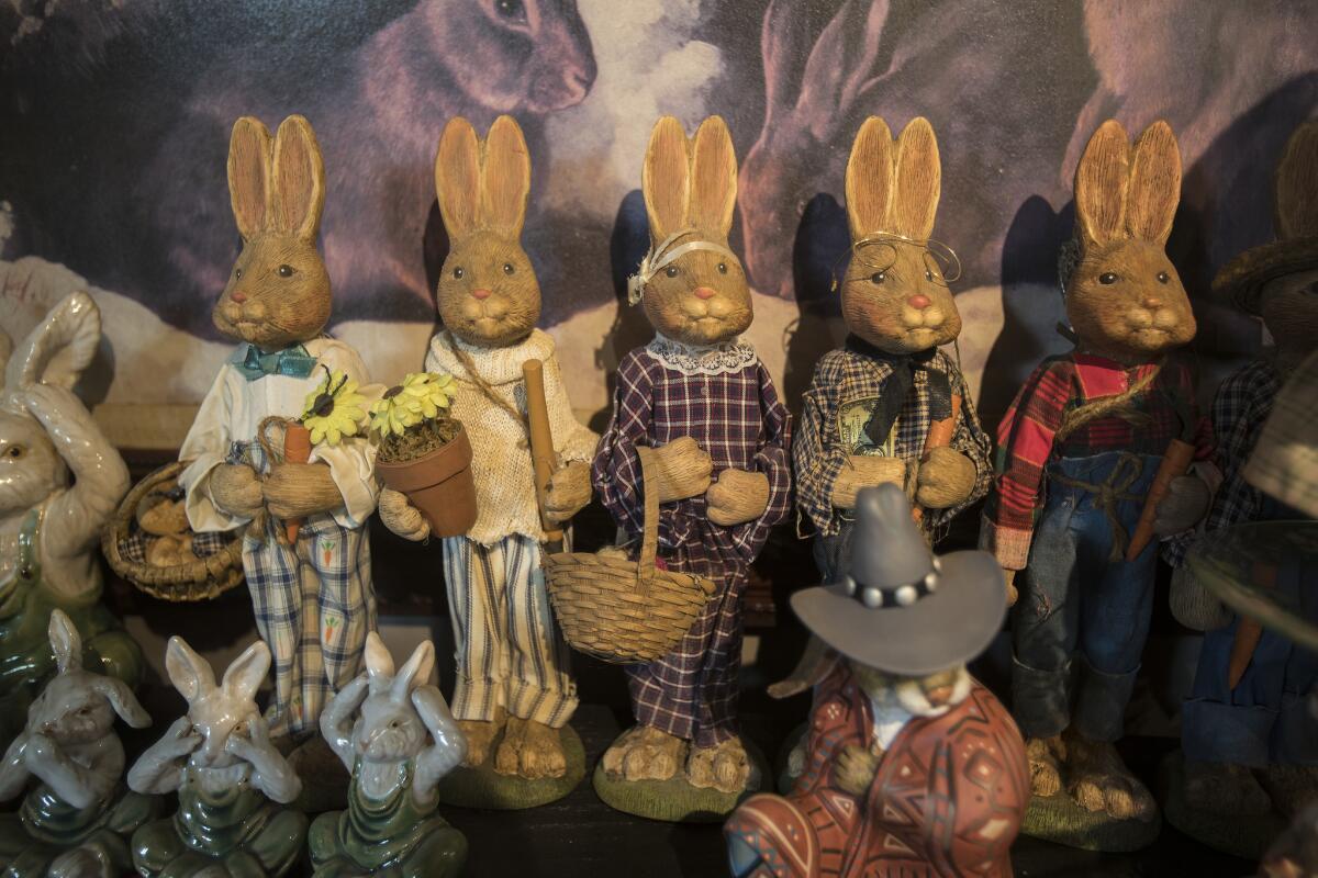 A family of bunnies made of resin stands in front of an oil painting at the Bunny Museum in Altadena in 2018.