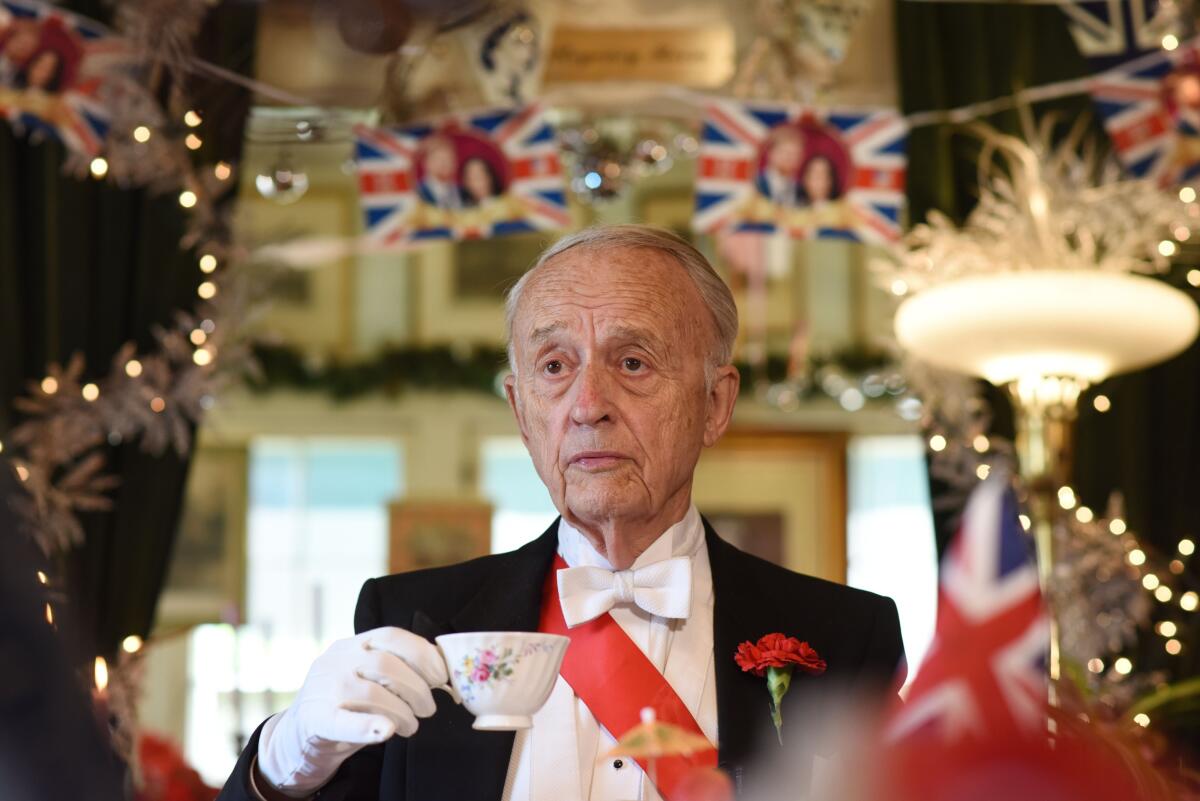 Rose Tree Cottage owner Edmund Fry, in formalwear, holds a teacup.