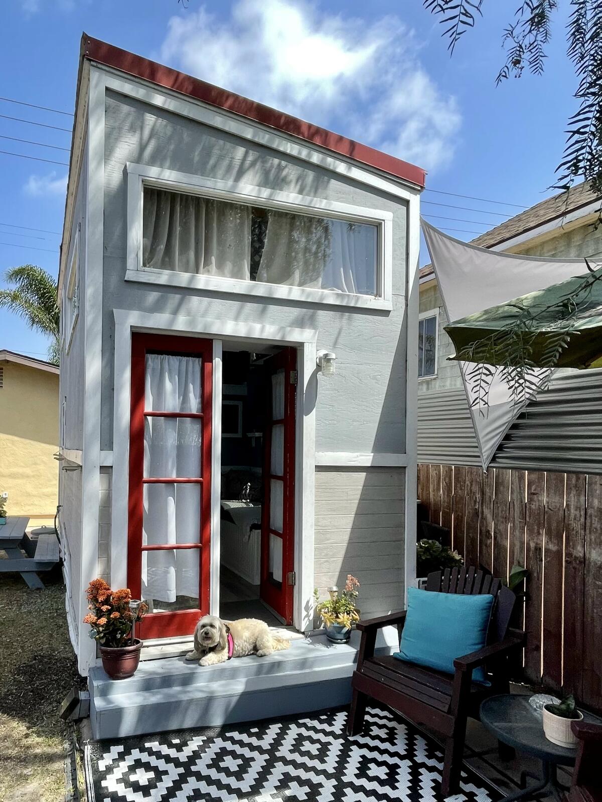 A two-story tiny house with French doors leading to a small patio