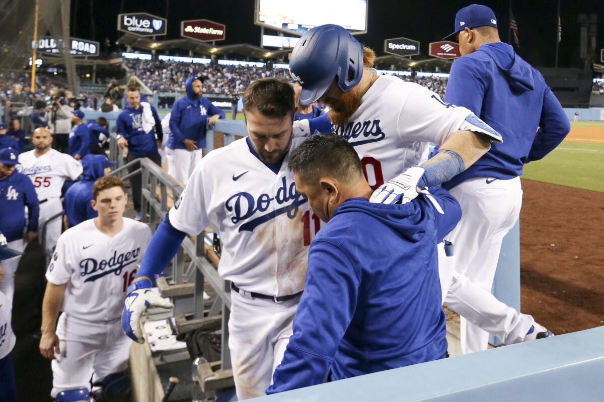 Justin Turner is helped into the dugout by AJ Pollock and a training staff member after hurting a hamstring.