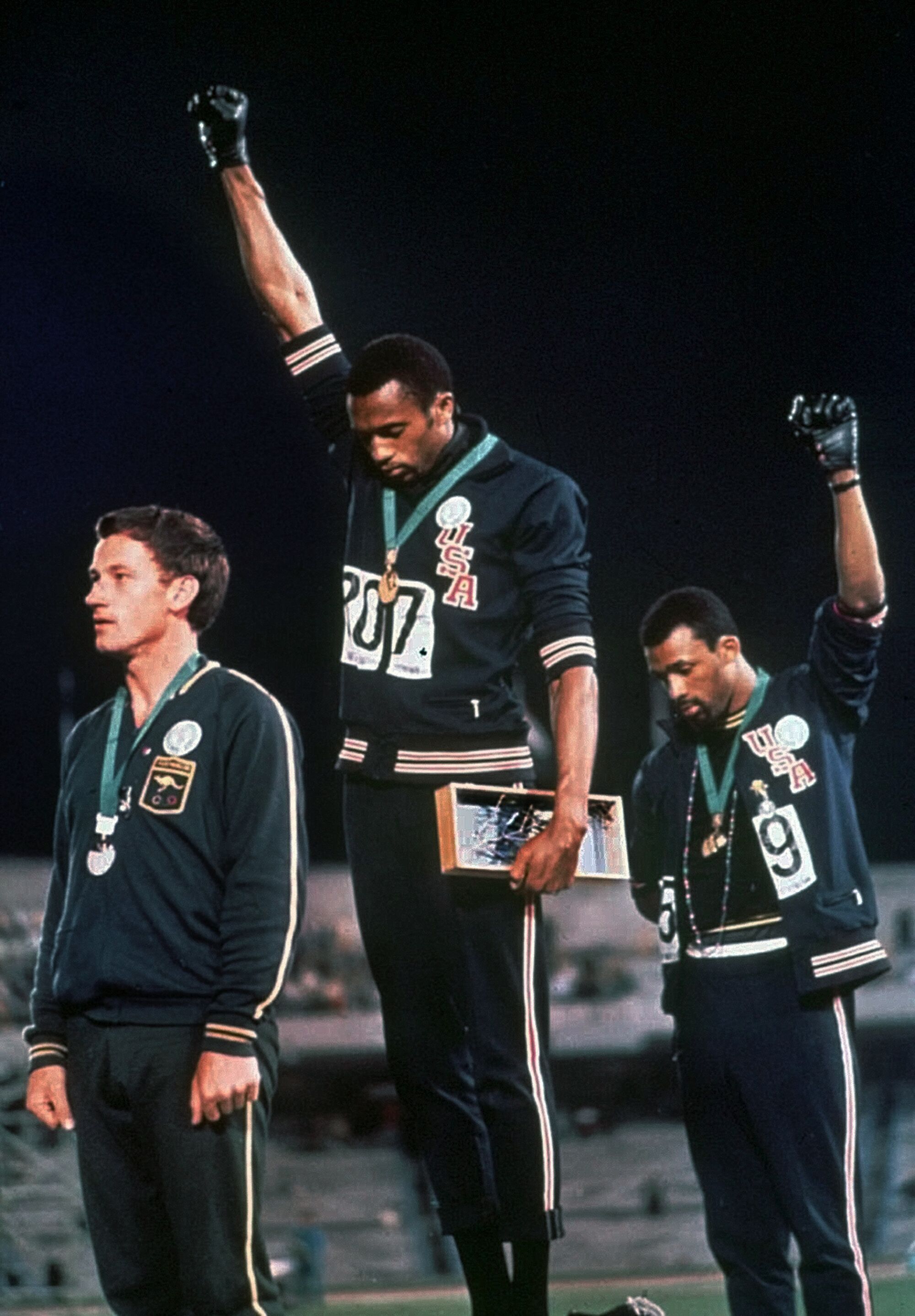 Los atletas estadounidenses Tommie Smith, al centro, y John Carlos, realizan el saludo Black Power en los Juegos Olímpicos de 1968.