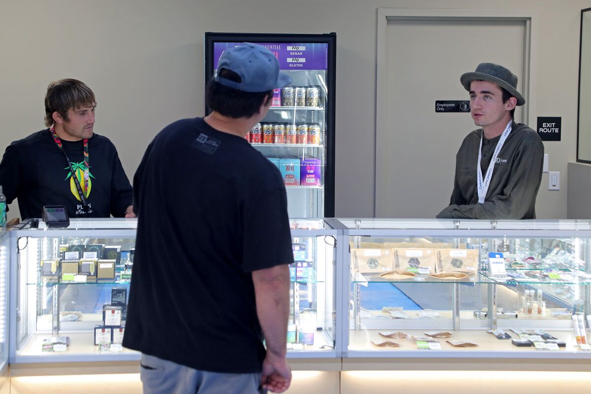 Budtenders Tyler Cormack, right, and Bryce Greer help a customer Wednesday at the newly opened 420 Central Newport Mesa.