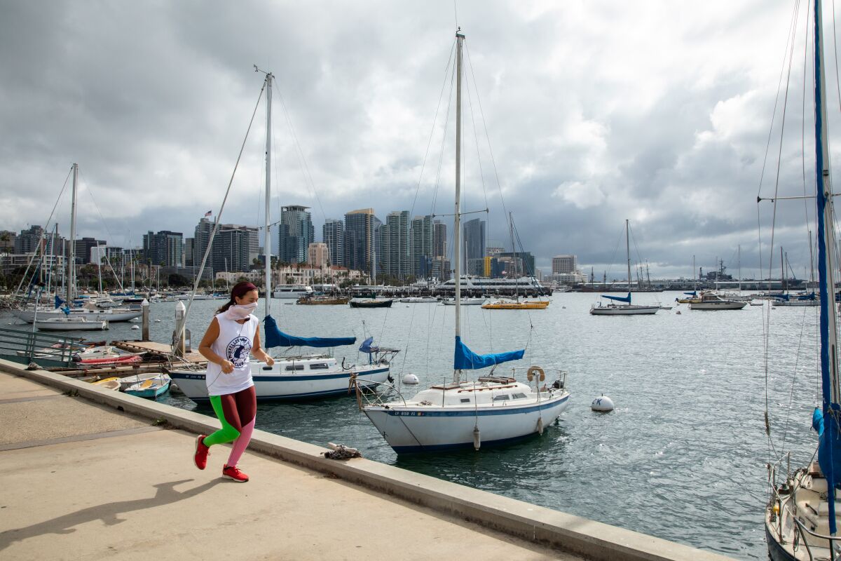 A jogger runs along Harbor Drive as storm clouds roll in over San Diego earlier this month.