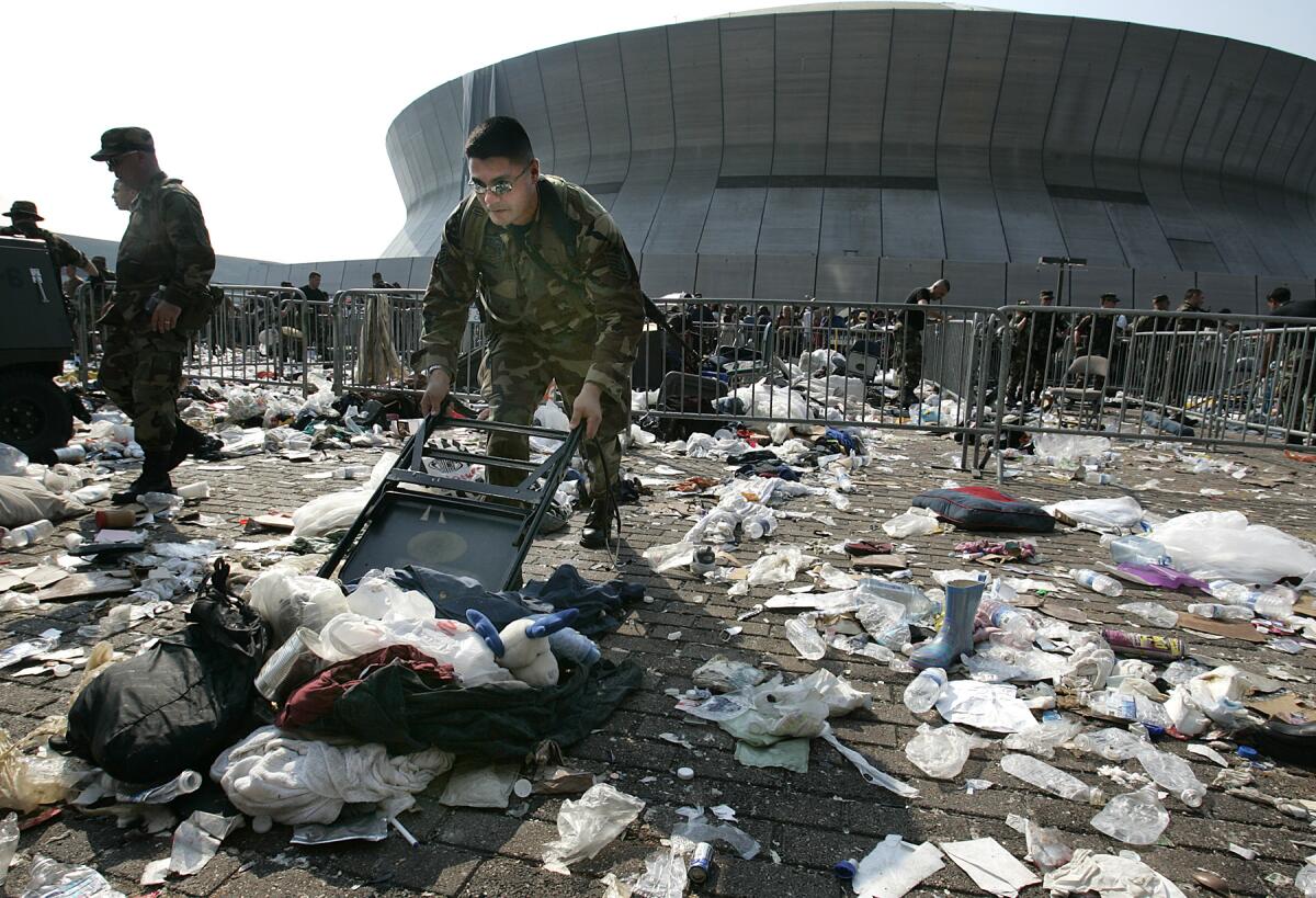 A member of the Texas Air National Guard uses a chair to sweep away a growing pile of debris.