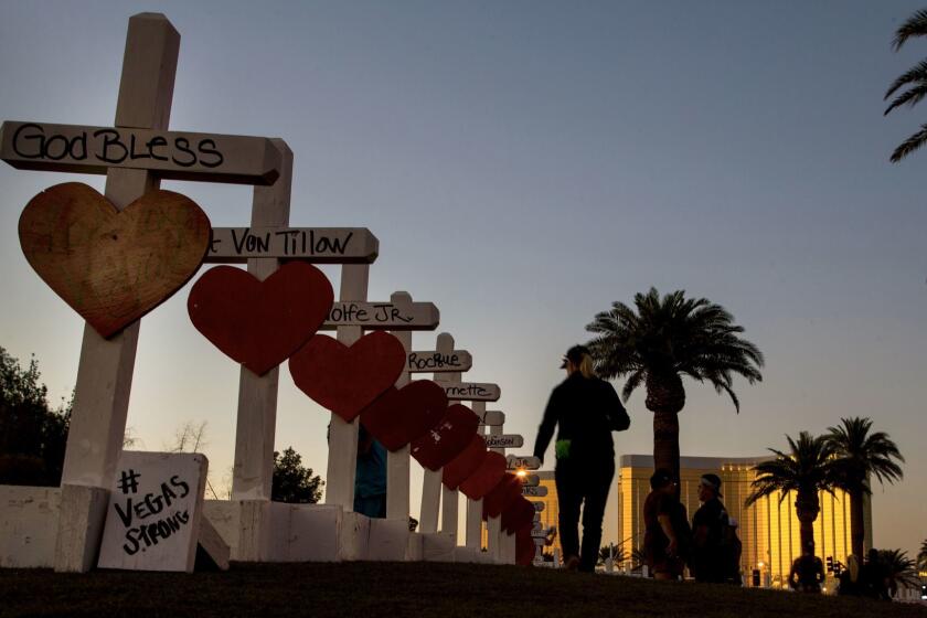 LAS VEGAS, NV - OCTOBER 5, 2017: Carol-Ann Seitzinger,62, of Las Vegas, runs her hand over the top of each wooden crosses bearing the names of those killed during Sunday's mass shooting off Las Vegas Boulevard on October 5, 2017 in Las Vegas, Nevada. Greg Zanis of Illinois drove all night to deliver the homemade crosses. (Gina Ferazzi / Los Angeles Times)