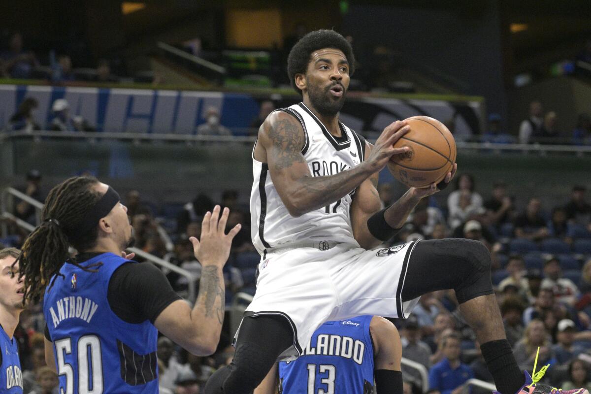 Brooklyn Nets guard Kyrie Irving (11) looks to pass after driving to the basket as Orlando Magic guard Cole Anthony (50) defends during the first half of an NBA basketball game Tuesday, March 15, 2022, in Orlando, Fla. (AP Photo/Phelan M. Ebenhack)