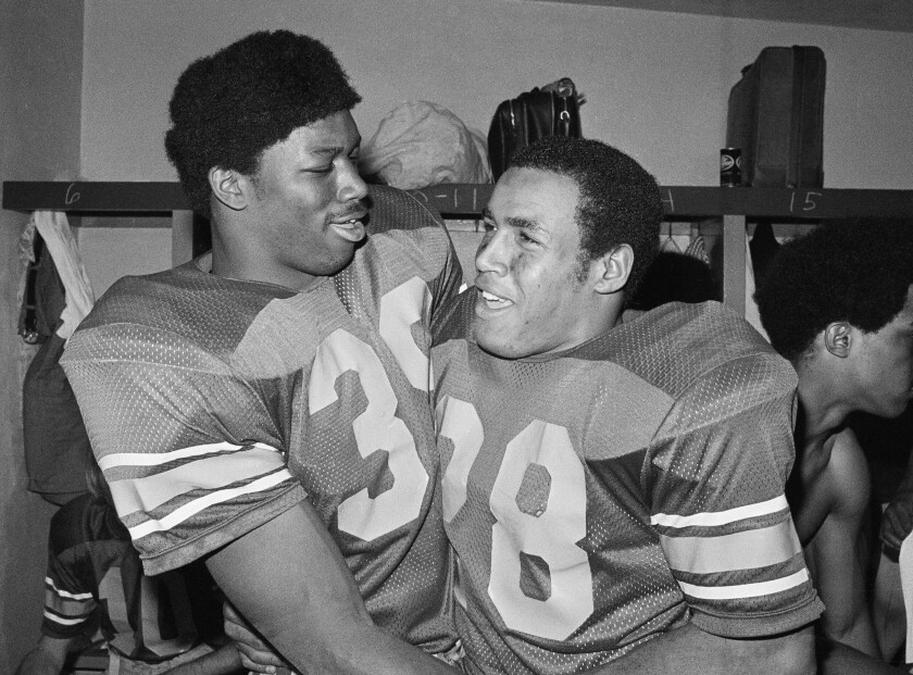 A young Sam Cunningham and Anthony Davis smile and hug.