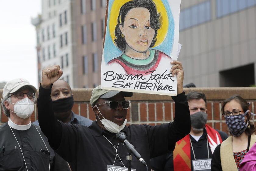 FILE - In this June 9, 2020, file photo, Kevin Peterson, center, founder and executive director of the New Democracy Coalition, displays a placard showing Breonna Taylor as he addresses a rally in Boston. Louisville's mayor says one of three police officers involved in the fatal shooting of Taylor will be fired, Friday, June 19, 2020. Taylor was gunned down by officers who burst into her Louisville home using a no-knock warrant. She was shot eight times by officers conducting a narcotics investigation. No drugs were found at her home. (AP Photo/Steven Senne, File)