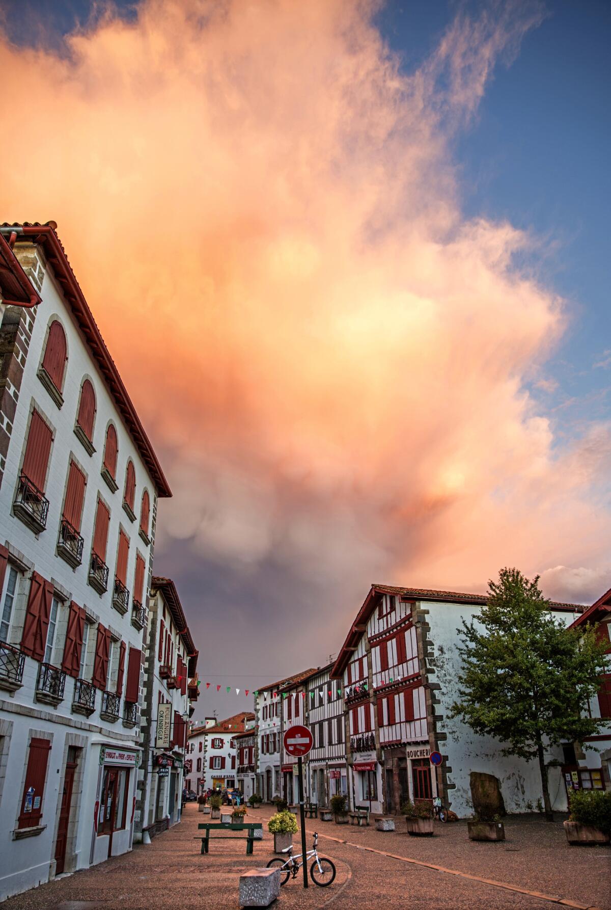 Looking down the street we see traditional white stone Labourd houses which feature timbered facades and stone lintels and shutters painted red.