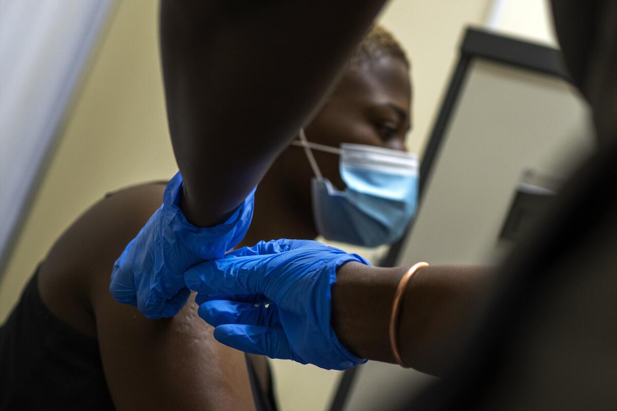 A gloved worker gives a woman a vaccine.