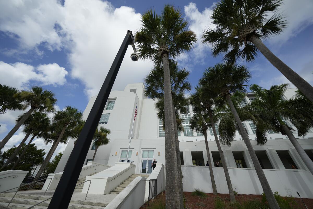 A white courthouse with palm trees in the foreground. 