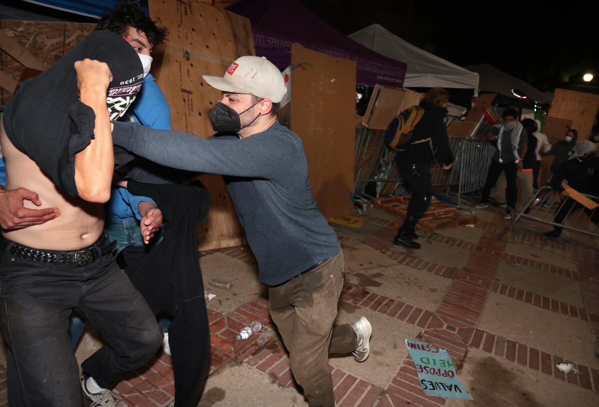 People scuffle at a protest.