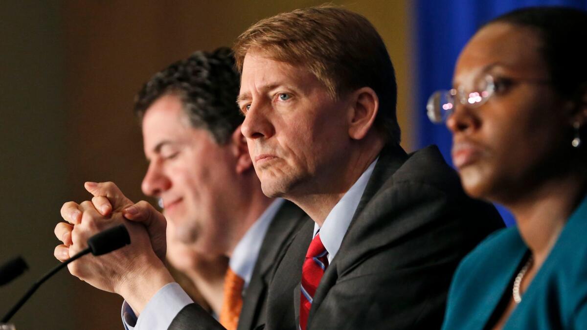 Consumer Financial Protection Bureau Director Richard Cordray, center, listens to comments during a panel discussion in Richmond, Va., in 2015.