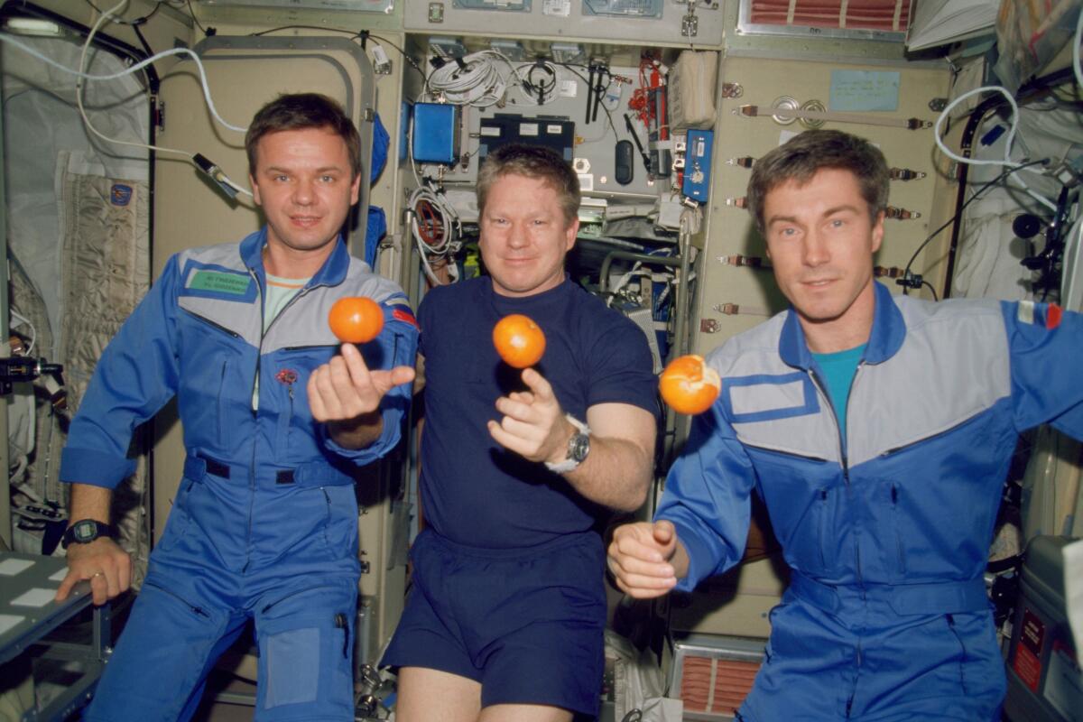 Expedition 1 crew members Yuri Gidzenko, from left, Bill Shepherd and Sergei Krikalev float with oranges on Dec. 4, 2000.