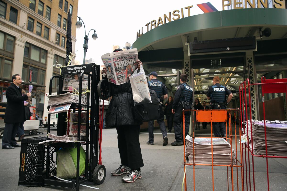 A woman reads the New York Post as police stand guard outside Penn Station in New York City.